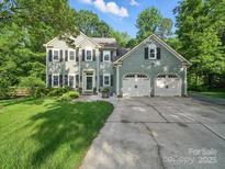 Charming two-story home with a well-manicured lawn, lush trees, and a two-car garage, offering curb appeal at 7344 Maitland Ln, Charlotte, NC 28215