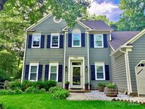 Charming two-story home with black shutters, a well-manicured lawn, and decorative plants at front door at 7344 Maitland Ln, Charlotte, NC 28215