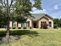Charming single-story home featuring a well-manicured lawn, mature trees, and welcoming curb appeal at 8429 Olde Stonegate Ln, Mint Hill, NC 28227