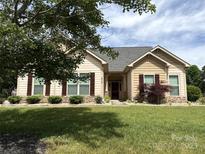 Charming single-story home featuring manicured lawn, stone accents, and complementary landscaping at 8429 Olde Stonegate Ln, Mint Hill, NC 28227