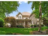 Charming two-story home with a stone and siding exterior, a welcoming front porch, and manicured landscaping at 8433 Cheverny Dr, Waxhaw, NC 28173