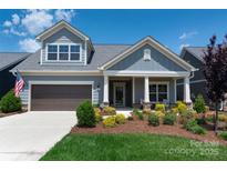 Charming two-story home featuring gray siding, a covered porch, manicured landscaping, and a two-car garage at 1006 Gradison Dr, Matthews, NC 28104