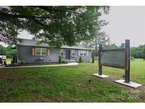 Charming gray brick home featuring a well-manicured lawn, shuttered windows, and inviting curb appeal at 1028 Washburn Switch Rd, Shelby, NC 28150
