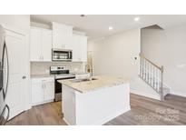 Modern kitchen features an island, stainless appliances, granite countertops, and stylish white cabinetry at 1423 Old Rivers Rd, Concord, NC 28027