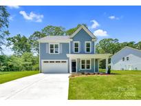 Charming two-story home featuring a manicured lawn, light blue siding, and a two-car garage at 1651 Carolina Cir, Gastonia, NC 28054