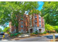 Beautiful vintage brick apartment building with a circular drive framed by mature trees and lush landscaping at 301 W 10Th St # 404, Charlotte, NC 28202