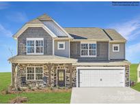 Two-story home showcasing stone accents, a covered porch, a two-car garage, and a well-manicured lawn at 4255 Skyboat Cir, Fort Mill, SC 29715