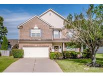 Two-story brick and vinyl home featuring manicured landscaping, a two-car garage and a welcoming front porch at 107 Golden Valley Dr, Mooresville, NC 28115