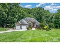 Charming home with stone accents, manicured lawn, and two-car garage nestled among mature trees at 145 Waterwood Dr, Shelby, NC 28150