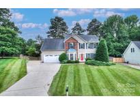 Charming two-story home with a well-manicured lawn, a red front door, and lush landscaping at 1633 Kiawah Ct, Gastonia, NC 28056