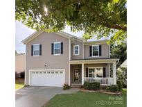 Charming two-story home featuring a welcoming front porch, attached garage, and manicured lawn at 1673 Beleek Ridge Ln, Clover, SC 29710