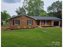 Charming single-story brick home featuring a well-manicured lawn and attached garage at 1713 Andover Nw St, Concord, NC 28027