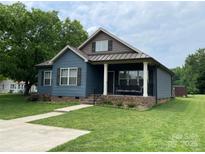 Charming blue home with a covered front porch and well-manicured lawn at 210 Rhyne St, Stanley, NC 28164