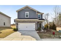 Two-story home featuring blue shingle siding, white garage doors, and manicured landscaping at 908 Smithcliffs Trl, York, SC 29745