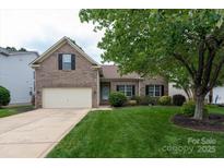 Charming brick home featuring a well-maintained lawn, mature trees, and attached two-car garage at 1003 Grayscroft Dr, Waxhaw, NC 28173