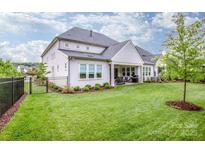 Beautiful backyard with a well-manicured lawn, covered patio, and dark metal fence at 13708 Huntson Park Ln, Huntersville, NC 28078
