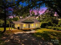 Charming one-story home featuring a covered porch, gravel driveway, and verdant lawn at 1528 Avondale Dr, Statesville, NC 28625