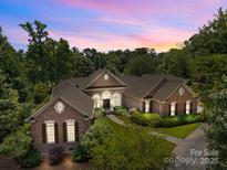 Stunning brick home with manicured landscaping and a beautiful sunset backdrop at 1629 Southpoint Ln, New London, NC 28127