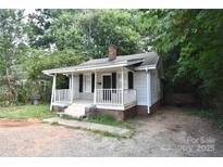 Quaint bungalow featuring a covered front porch and brick foundation, surrounded by mature trees at 2017 Ashley Rd, Charlotte, NC 28208