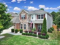 Charming two-story home with manicured lawn, stone accents, and a welcoming American flag at 5424 Tilley Manor Dr, Matthews, NC 28105