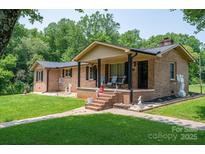 Charming brick home with covered porch, manicured lawn, and mature trees offers a welcoming curb appeal at 5958 Hoover Elmore Rd, Lincolnton, NC 28092