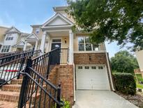 Charming townhome featuring a one-car garage and inviting entrance with brick accents and black railing at 7130 Founders Club Ct, Charlotte, NC 28269