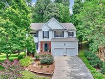 Traditional two-story home with a well-manicured lawn and driveway leading to a two-car garage at 14203 Queens Carriage Pl, Charlotte, NC 28278