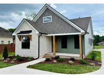 Charming home featuring stone accents, gray siding, inviting porch, and professionally landscaped front yard at 1721 S New Hope Rd, Gastonia, NC 28054
