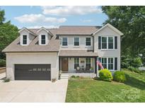 Charming brick home featuring dormer windows, attached garage, inviting front porch, and manicured lawn at 207 Spaniel Se Dr, Concord, NC 28025