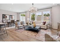 Open-concept living room featuring stylish decor, wood floors, large windows and an adjacent dining area at 507 Webster Ln, Cramerton, NC 28032