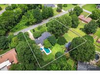 Aerial view of a beautiful property featuring a large pool, mature trees, and a well-maintained lawn at 6313 Weddington Rd, Concord, NC 28027