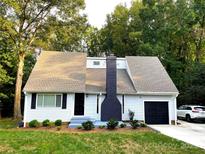 Charming single-Gathering home with a well-manicured lawn, black trim, and a matching chimney and garage door at 10101 Wood Ct, Charlotte, NC 28277