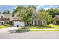 Charming two-story brick home with manicured front yard and attached two-car garage on a sunny day at 10106 Silverling Dr, Waxhaw, NC 28173
