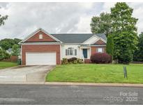 Charming home featuring a brick and vinyl exterior, attached garage and a well-manicured front lawn at 116 Birchwood Ct, Mount Holly, NC 28120