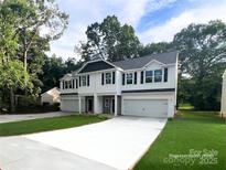 New construction townhome with white siding, black shutters, gray stone accents, and a spacious driveway in a landscaped community at 12526 Susanna Dr, Charlotte, NC 28214