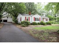 Charming single-story home featuring red shutters, mature trees, and an adjacent detached garage at 1270 N Enochville Ave, China Grove, NC 28023