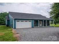 Charming teal home featuring a spacious two-car garage and a welcoming covered front porch with stone gravel at 3103 Richview Dr, Crouse, NC 28033