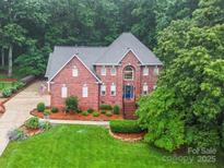 Stunning two-story brick home boasts a lush landscaped yard and mature trees at 4644 Snow Dr, Harrisburg, NC 28075