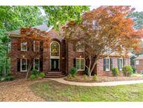 Charming brick home featuring mature trees, manicured lawn, and a welcoming front entrance at 4672 Snow Dr, Harrisburg, NC 28075