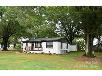 Charming one-story home featuring a crisp white exterior with modern black trim and a welcoming front porch at 706 Mcintyre St, Monroe, NC 28110