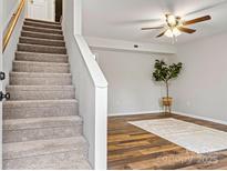 View of the living room featuring carpeted stairs, hardwood floors, and a ceiling fan at 729 Tenth Ne Ave, Hickory, NC 28601
