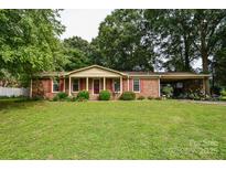 Charming brick ranch home with a welcoming front porch and well-manicured lawn at 7518 Surry Ln, Indian Trail, NC 28079