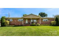 Charming brick home with well-manicured lawn and inviting covered front porch with chairs for relaxing at 110 Heritage Dr, Kings Mountain, NC 28086