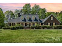 Charming brick home with a welcoming front porch, manicured lawn and mature landscaping at 127 Fantasy Ln, Mooresville, NC 28117