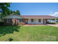 Charming brick home featuring a well-manicured lawn, covered porch, and convenient carport at 1613 Spangler Dr, Shelby, NC 28150