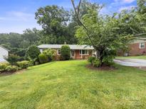 Charming single-story home featuring a brick facade, lush green lawn, and mature trees at 46 Donna Dale Se Ave, Concord, NC 28025