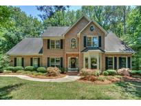 Traditional brick home featuring a manicured lawn, mature trees, and classic black shutters at 5485 Deer Run Ct, Davidson, NC 28036