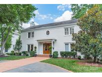 Charming two-story white brick home with mature trees, a brick driveway, and manicured landscaping at 601 Cherokee Rd, Charlotte, NC 28207