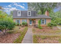 Charming two-story brick home with blue shutters and a landscaped front yard with a wooden porch swing at 6577 Stoney Ridge Rd, Matthews, NC 28104
