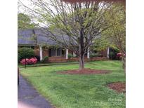 Charming brick home featuring a lush green lawn, mature trees, and colorful azalea bushes at 106 Condover Pl, Charlotte, NC 28270